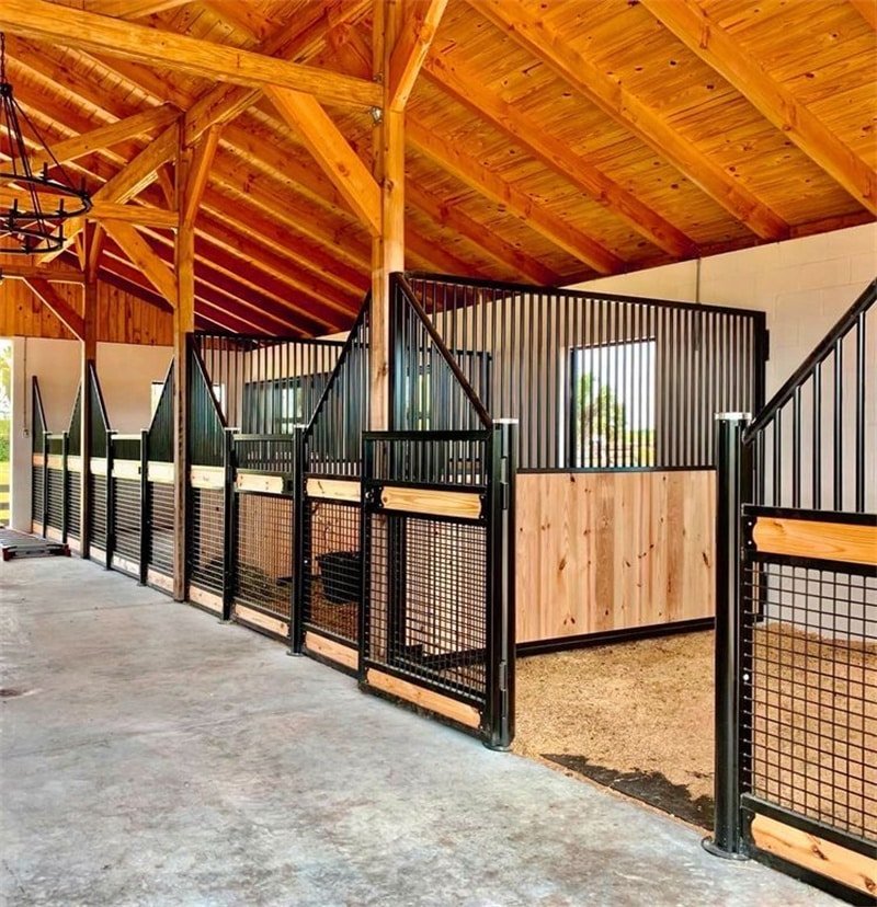 A rustic-style stable with wooden beams and open-air stalls, featuring steel and wood combinations for a durable and attractive design.