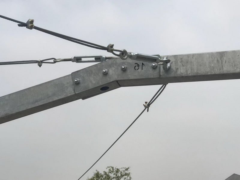Close-up of a galvanized steel horse walker arm joint with wire rope rigging, turnbuckles and bolted connections